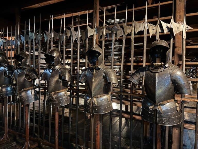 Eine Reihe mittelalterlicher Rüstungen im Landeszeughaus, dem steirischen Zeughaus in Graz, Österreich. Der schummrig beleuchtete Raum ist voller Rüstungen und Waffen, die die Geschichte der militärischen Ausrüstung zeigen. Das Landeszeughaus ist eines der bedeutendsten Museen in Graz und bietet einen Einblick in seine umfangreiche Sammlung von Waffen und Rüstungen aus der Vergangenheit.