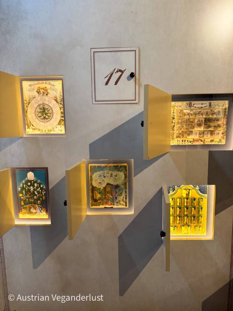 A wall display featuring illuminated Advent calendars in the Salzburg Christmas Museum. Each open panel reveals vintage-style holiday scenes, adding a nostalgic charm to the festive exhibit.
