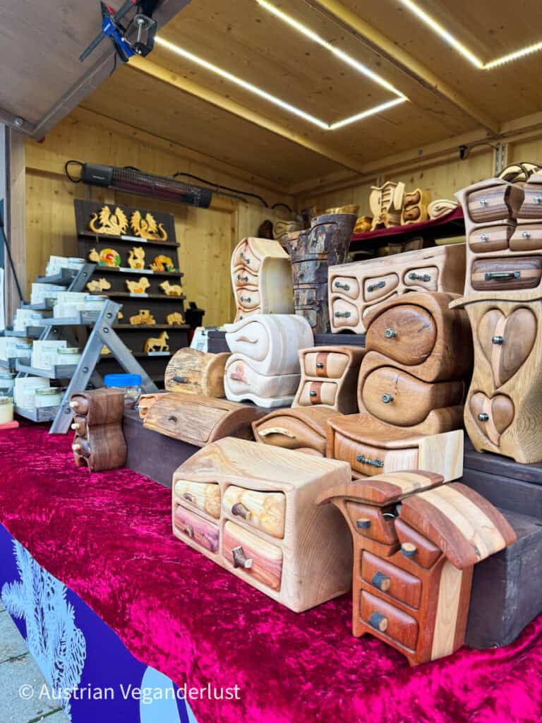 Display of handcrafted wooden jewelry boxes with whimsical, curved designs and natural wood grain finishes, for sale at a Linz Christmas market stall.