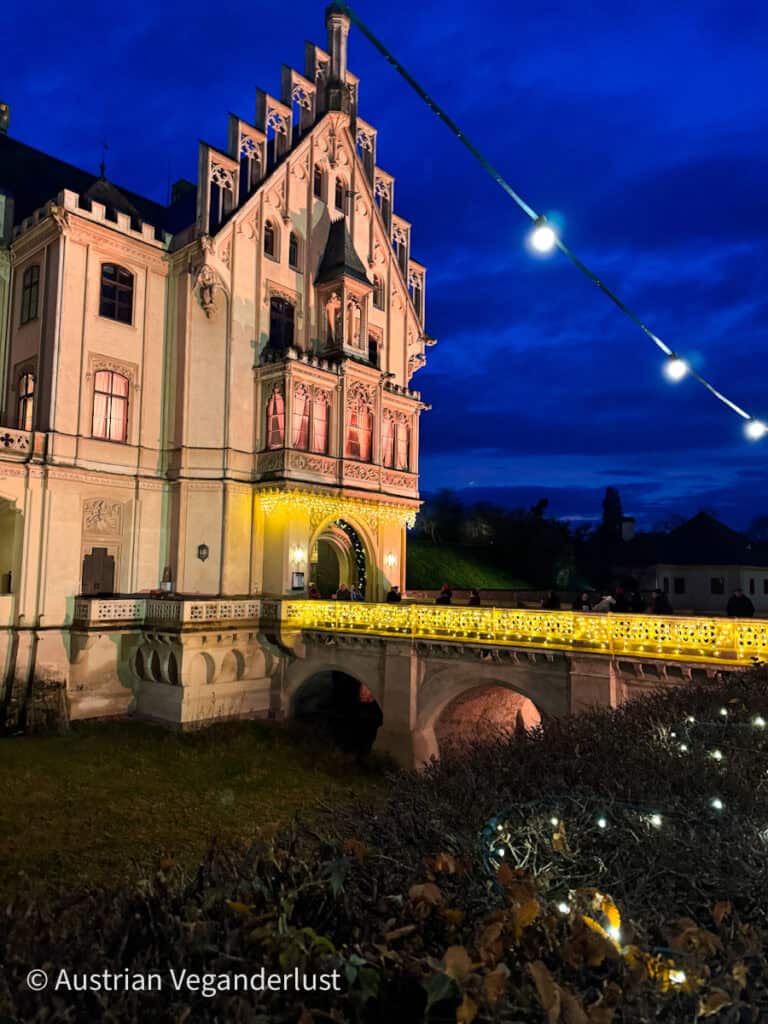 Grafenegg Castle beautifully illuminated at night, with festive lights on the bridge welcoming guests to the Christmas market.