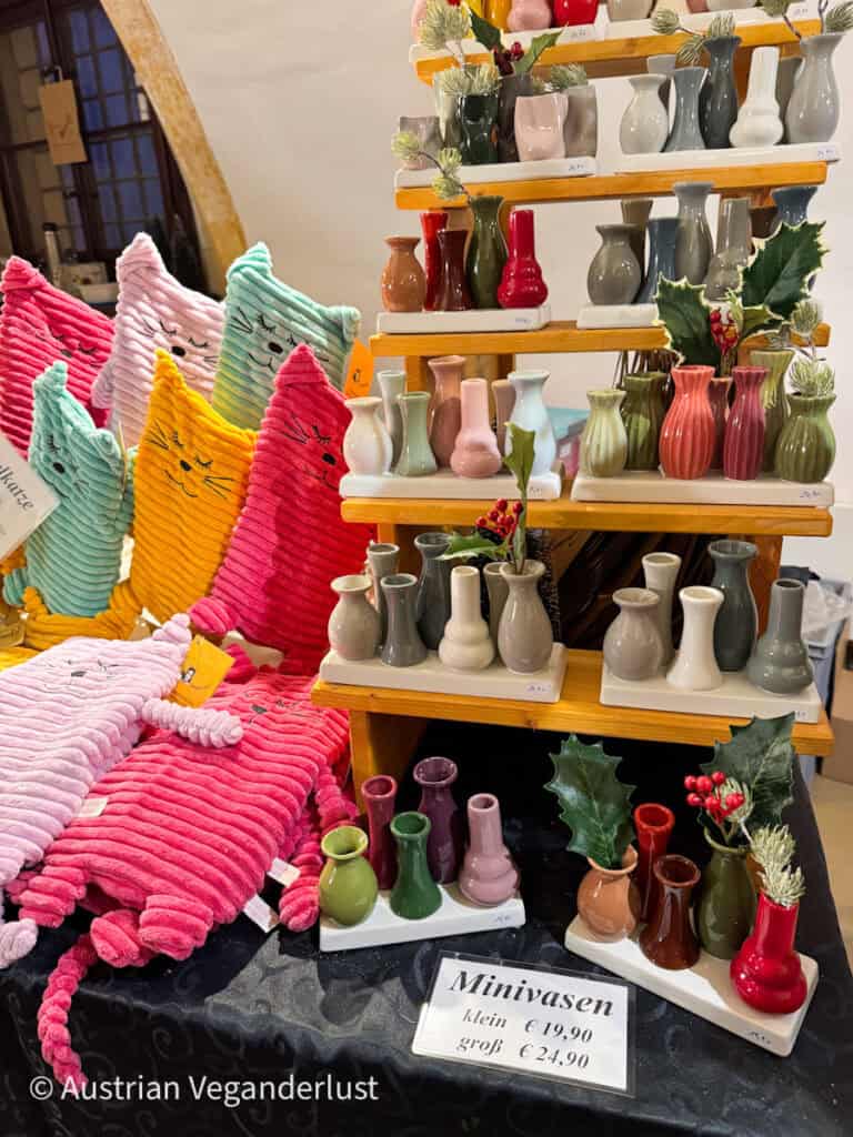 Colorful mini ceramic vases and whimsical soft toys displayed at a craft stall inside Grafenegg Castle’s Christmas market.