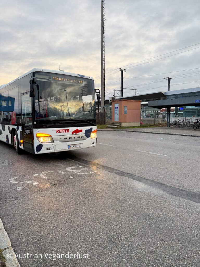 A shuttle bus from Retter Reisen parked in front of a train station under a cloudy sky, ready to transport visitors to the Christmas market.