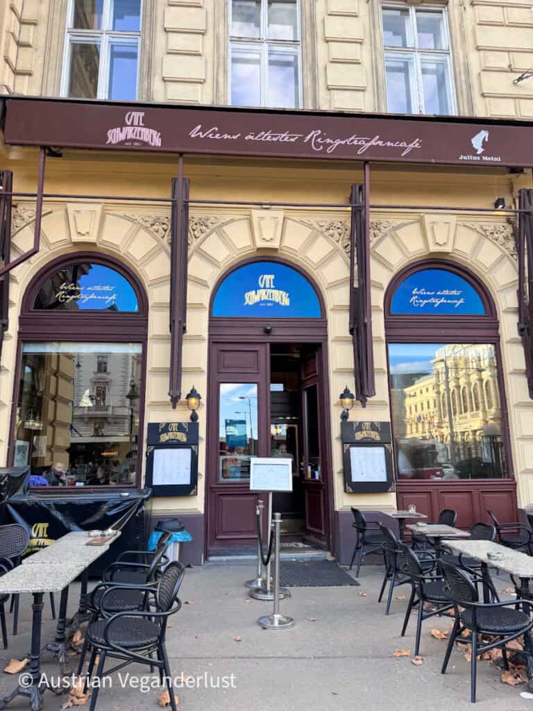 Außenansicht eines klassischen Wiener Kaffeehauses mit Sitzplätzen im Freien, über dem Eingang ein Schild mit der Aufschrift "Café Schwarzenberg" und "Wien ältestes Ringstraßencafé".